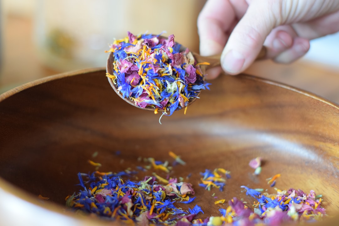 dried colourful flower petals in a wooden bowl representing what are adaptogens and the diversity of medicinal herbs